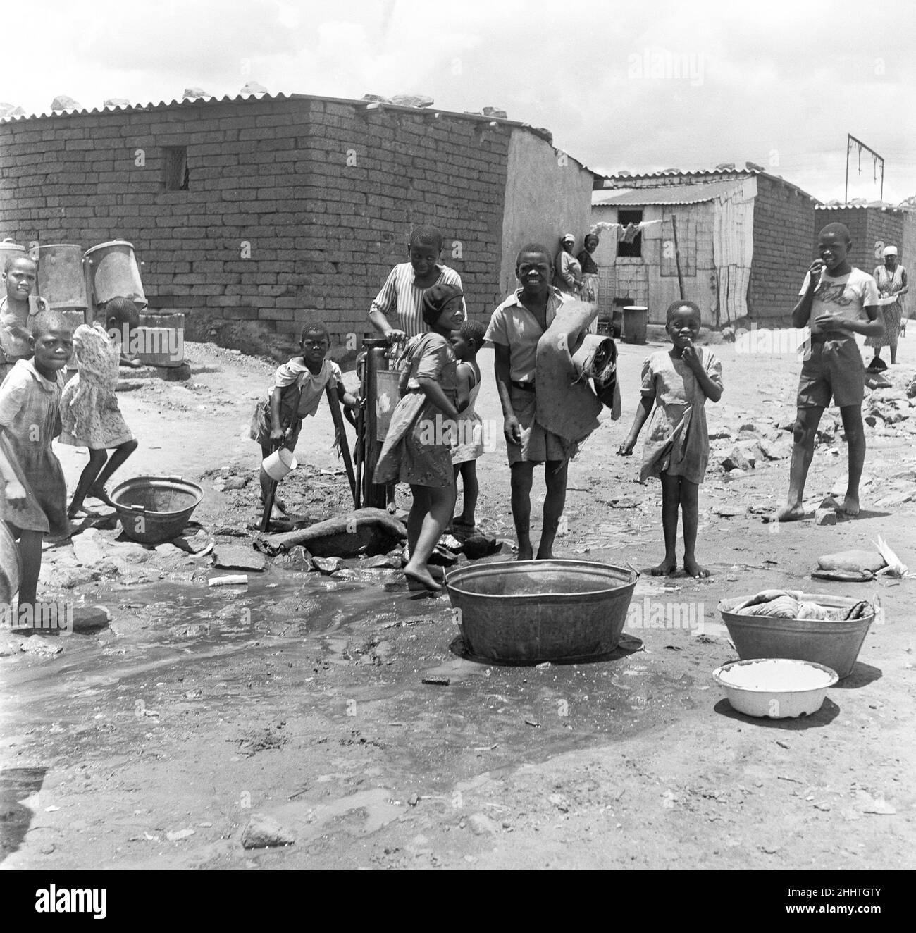 Bambini alla pompa dell'acqua nella cittadina di Windermere, vicino a Città del Capo che raccoglie l'acqua. 4th febbraio 1955 Foto Stock