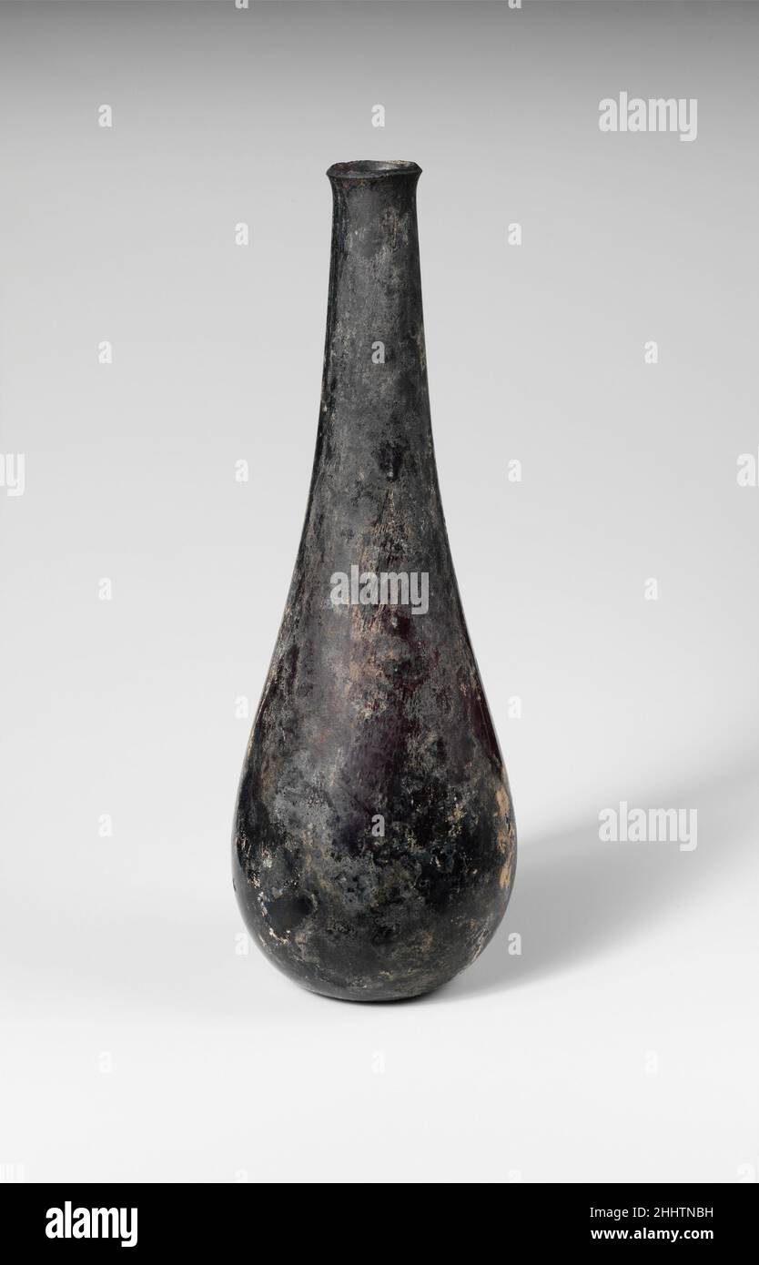 Bottiglia di vetro ca. 4th–5th secolo d.C. romano traslucido viola profondo. Bordo leggermente rovesciato, con labbro esterno smussato; collo alto, cilindrico, che si espande verso il basso e si unisce impercettibilmente con corpo piriforme; fondo leggermente concavo.intatto; scolorimento, vaiolatura e iridescente. Bottiglia di vetro 245638 Foto Stock