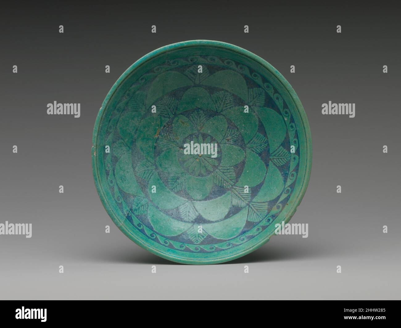 Ciotola 200–150 a.C. ? Periodo tolemaico la decorazione a rilievo di questa ciotola poco profonda è esaltata dal contrasto tra il suo colore turchese chiaro primario e il blu scuro utilizzato negli interstizi e sullo sfondo. All'esterno, cinque petali del loto nelumbo intervallati con le punte dei petali interni di loto e le foglie nervate di una pianta sconosciuta circondano la base come un fiore. All'interno, tre anelli di petali di nelumbo e foglie nervate racchiudono la rosetta centrale; un modello a cresta d'onda e una banda piana circondano l'intero.le ciotole erano parte della produzione diffusa di faience in Hellenistic ed Imperial R. Foto Stock