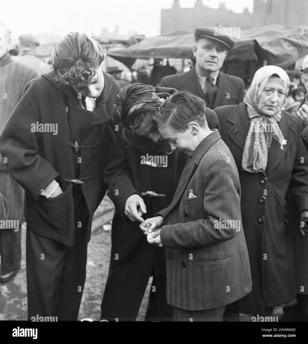 Un giovane collezionista di francobolli mostra i suoi ultimi acquisti alla sua collezione ai suoi amici al mercato delle pulci di Club Row, Bethnal Green, E1 Londra 1st marzo 1955 Foto Stock
