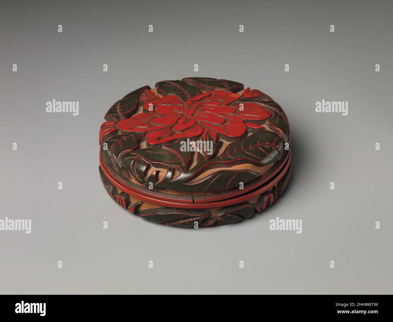 Box con camellia 14th secolo Cina i fiori stilizzati raffigurati in lacca cinese sono spesso difficili da identificare con precisione. Tuttavia, il grande fiore su questa scatola è probabilmente una camelia, un fiore associato con l'inverno e la resistenza. Questa scatola è uno dei molti, più trovati in Giappone, che portano il nome Zhang Cheng (qui, scolpito nella base). È uno dei soli due artisti laccati del XIV secolo i cui nomi sono registrati. Scatola con camellia 60910 Foto Stock
