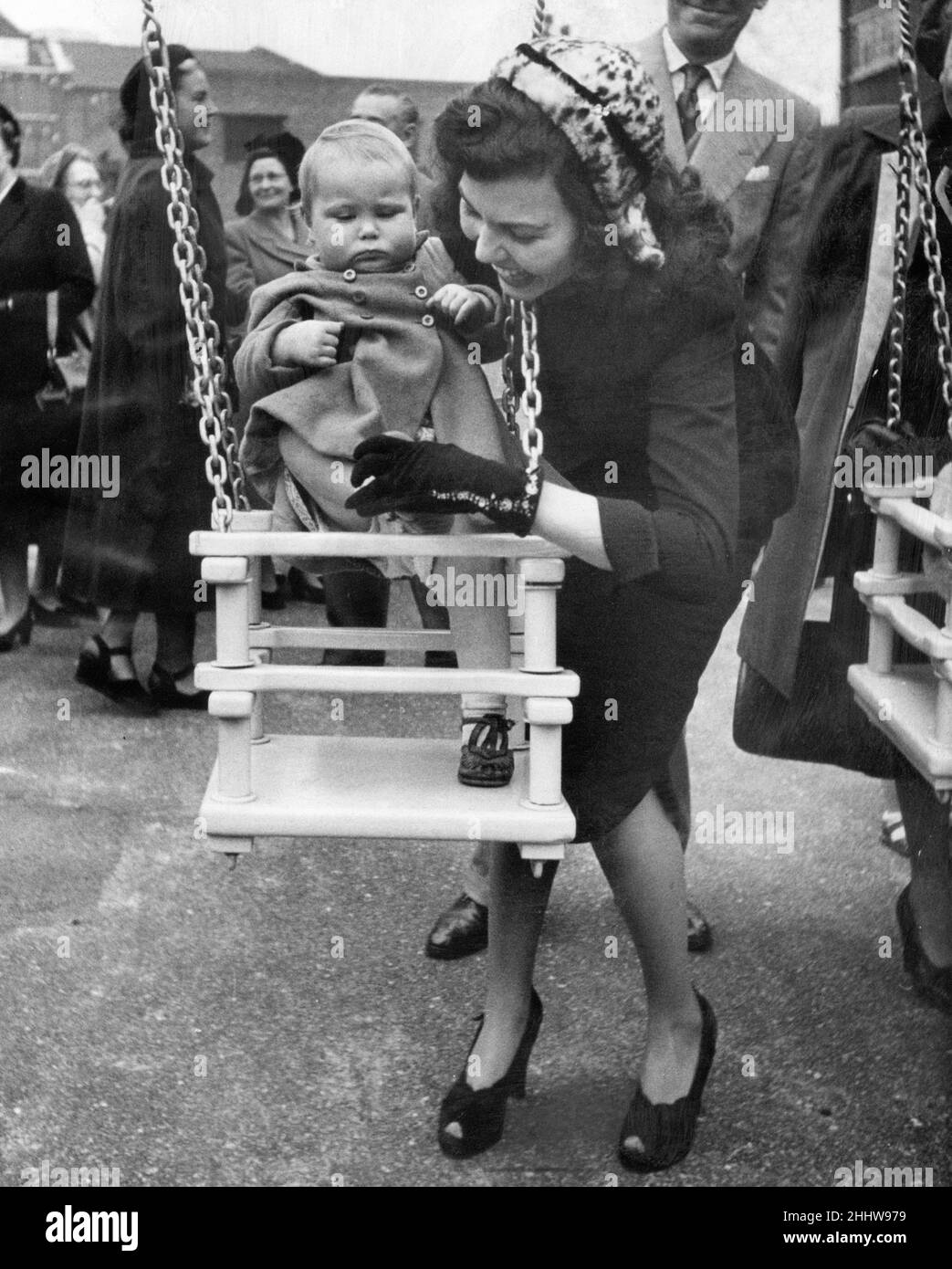 Cerimonia di apertura, Variety Playground, Arnold Estate, Bermondsey, South East London, Mercoledì 3rd ottobre 1951. La nostra foto mostra ... l'attrice Simone Silva aiuta un bambino in un'oscillazione dopo l'apertura. Il parco giochi è stato costruito con i proventi di un matinee di mezzanotte in scena dal Variety Club di Gran Bretagna nel settembre 1949. Il club ha utilizzato il ¿6.000 che hanno sollevato per aiutare a tenere i londinesi piccoli lontano dai pericoli dei giochi di strada. Il parco giochi è stato costruito su quello che era un sito bombardato alla Arnold Estate a Bermondsey. Foto Stock