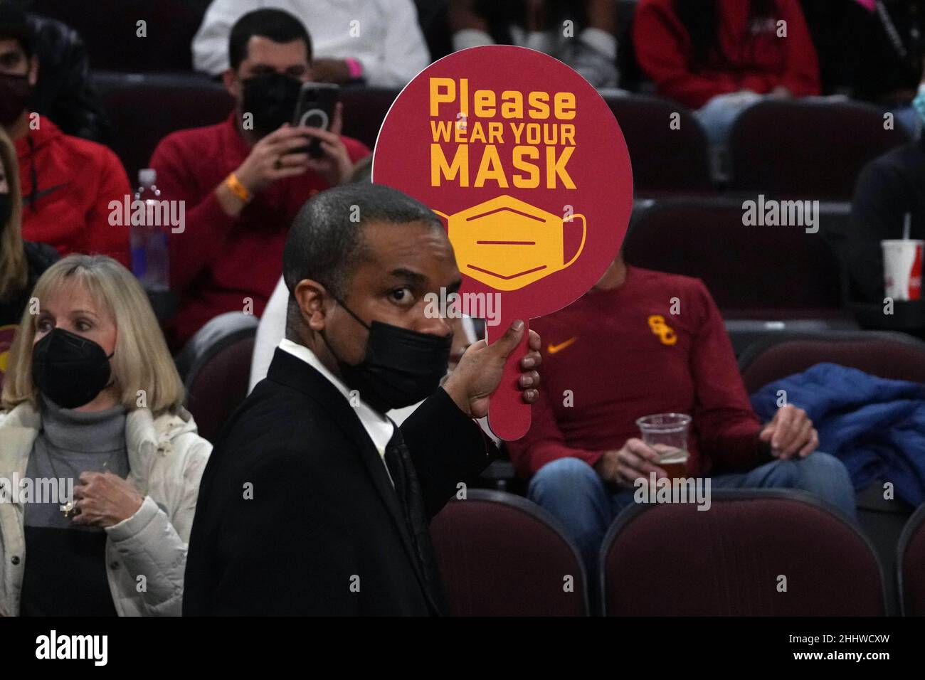 Un usciere tiene in mano un cartello con la scritta "Please wear a (face) mask" durante una partita di basket NCAA tra i Southern California Trojans e gli Arizona State Sun Devils in mezzo all'ondata della variante COVID-19 omicron, lunedì 24 gennaio 2022, a Los Angeles. Foto Stock