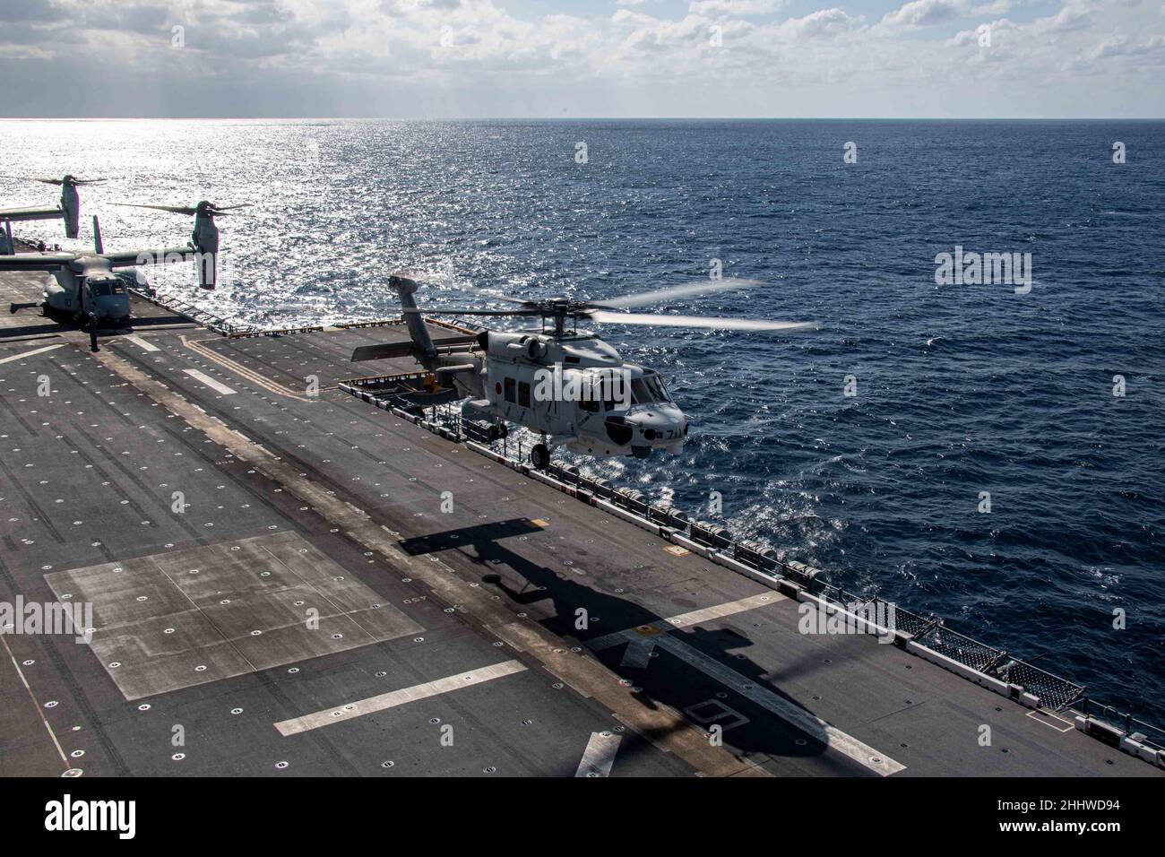 MAR DELLE FILIPPINE (Gen. 20, 2022) un elicottero SH-60K Sea Hawk della nave Japan Martime Self-Defense Force JS Hyuga (DDDH 181) atterra sul ponte di volo della nave d'assalto anfibio dispiegata in avanti USS America (LHA 6). L'America, nave principale dell'America Amphibious Ready Group, insieme all'unità Marine Expeditionary 31st, sta operando nell'area di responsabilità della flotta USA 7th per migliorare l'interoperabilità con alleati e partner e servire come forza di risposta pronta per difendere la pace e la stabilità nella regione IndoPacifico. (STATI UNITI Foto Navy di SMass Communication Specialist Seaman Matthew Bake Foto Stock