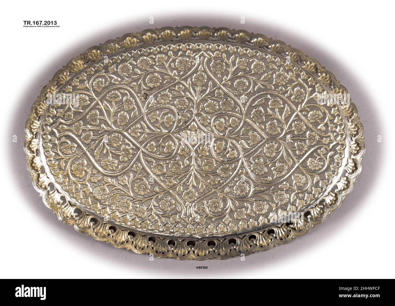 Vassoio dorato d'argento fine 18th secolo questo vassoio mostra l'influenza europea nella sua forma ovale (vassoi indiani generalmente di forma rotonda), mentre i motivi decorativi frondosi richiamano anche in modo lasco profili ispirati al vaso che erano popolari in dipinti, tessuti e sculture in tutta la regione. La natura dell'ornamento combina un gusto di lunga data nel Decano per la decorazione a base arabesca, con un equilibrio e una simmetria che indicano il gusto Mughal. Vassoio dorato argento. Fine 18th secolo. Argento; dorato. Dall'India, Hyderabad. Metallo Foto Stock