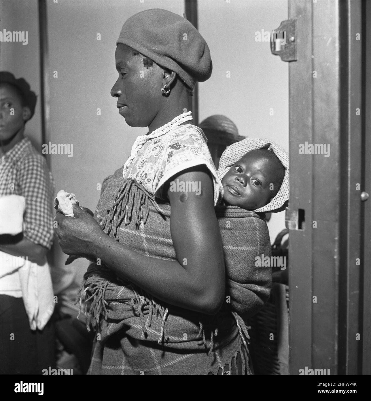 Madre che porta il suo bambino in un papoose, frequenta una clinica sanitaria locale nella cittadina di Langa vicino a Città del Capo. 4th febbraio 1955 Foto Stock