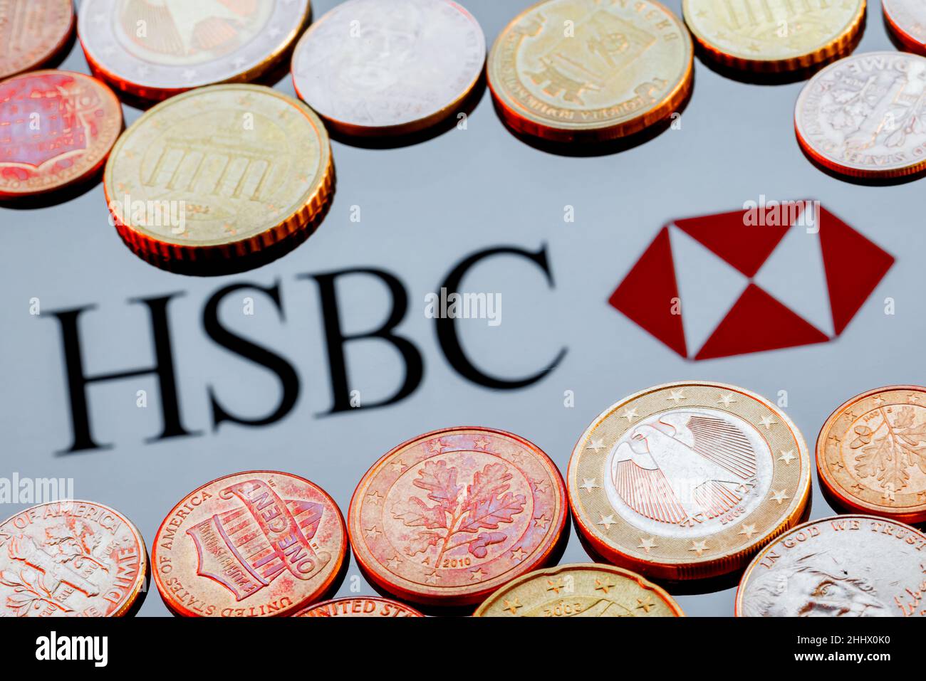 Varietà di monete metalliche sullo sfondo del logo della banca HSBC Foto Stock