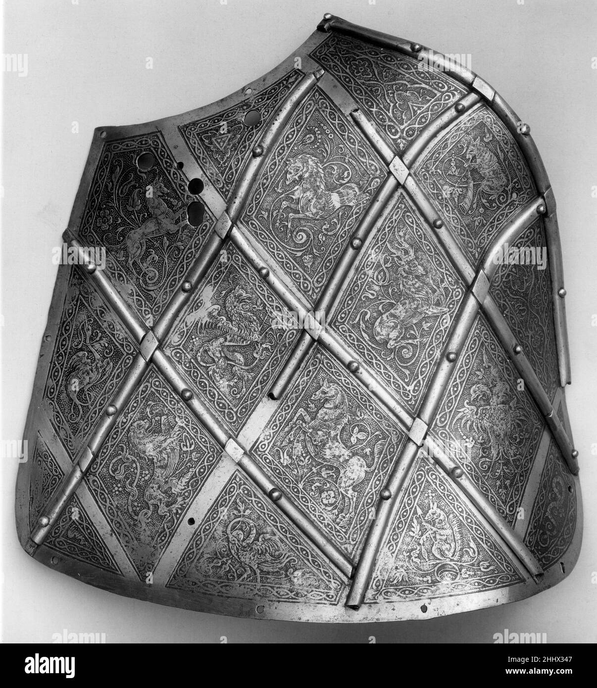 Trellised Targe per il Tilt ca. 1550–60 Tedesco, Augsburg nel mantenere il punteggio ai tornei, gli araldi hanno assegnato punti extra se una lancia ha colpito abbastanza saldamente per rompersi. Le fasce trellislike sollevate su questa targe tilt erano destinate a catturare la lancia, rendendola più probabile a frantumarsi. Le aree all'interno del trellis sono finemente incise con un'inventiva menagerie di animali reali e fantastici, tra cui un leone, un cavallo, un griffin, e un'aquila imperiale a doppia testa. Trellised Targe per il Tilt. Tedesco, Augsburg. Ca. 1550–60. Acciaio, oro. Augusta. Protezioni Foto Stock