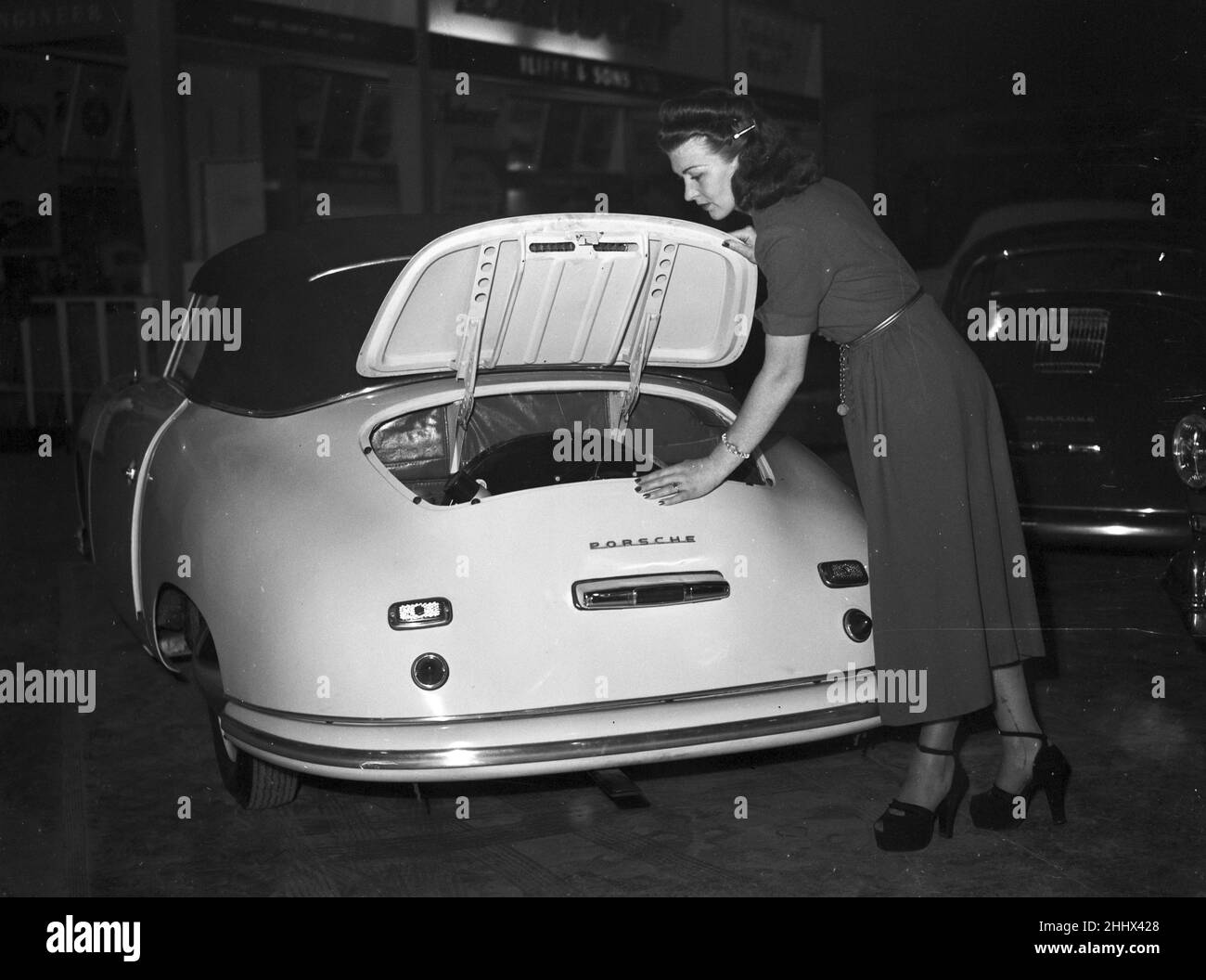 British International Motor Show, tenuto a Earls Court, Londra, dal 17th al 27th ottobre 1951. Nella foto, il modello ammira il bagagliaio della vettura Porsche. Foto Stock