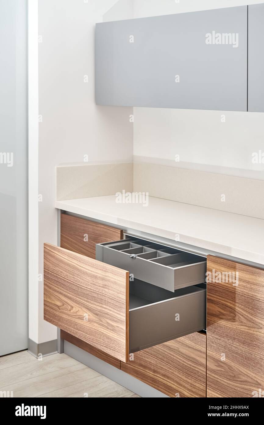 Cassetti aperti di colore grigio scuro con vassoio posate in cucina contemporanea di legno di noce e colore grigio con superficie solida acrilica piano primo piano Foto Stock