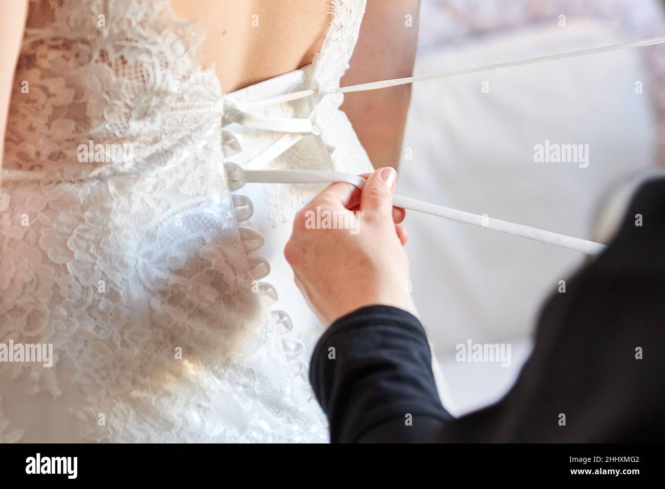 Una femmina aiuta una sposa a prepararsi per il matrimonio Foto Stock