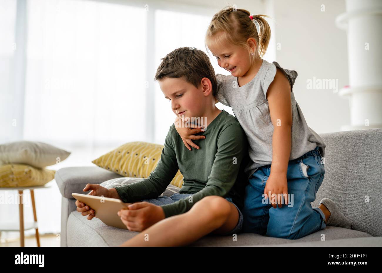 Bambina e ragazzo che guardano video o giocano con i loro dispositivi digitali, tablet e smartphone. Foto Stock
