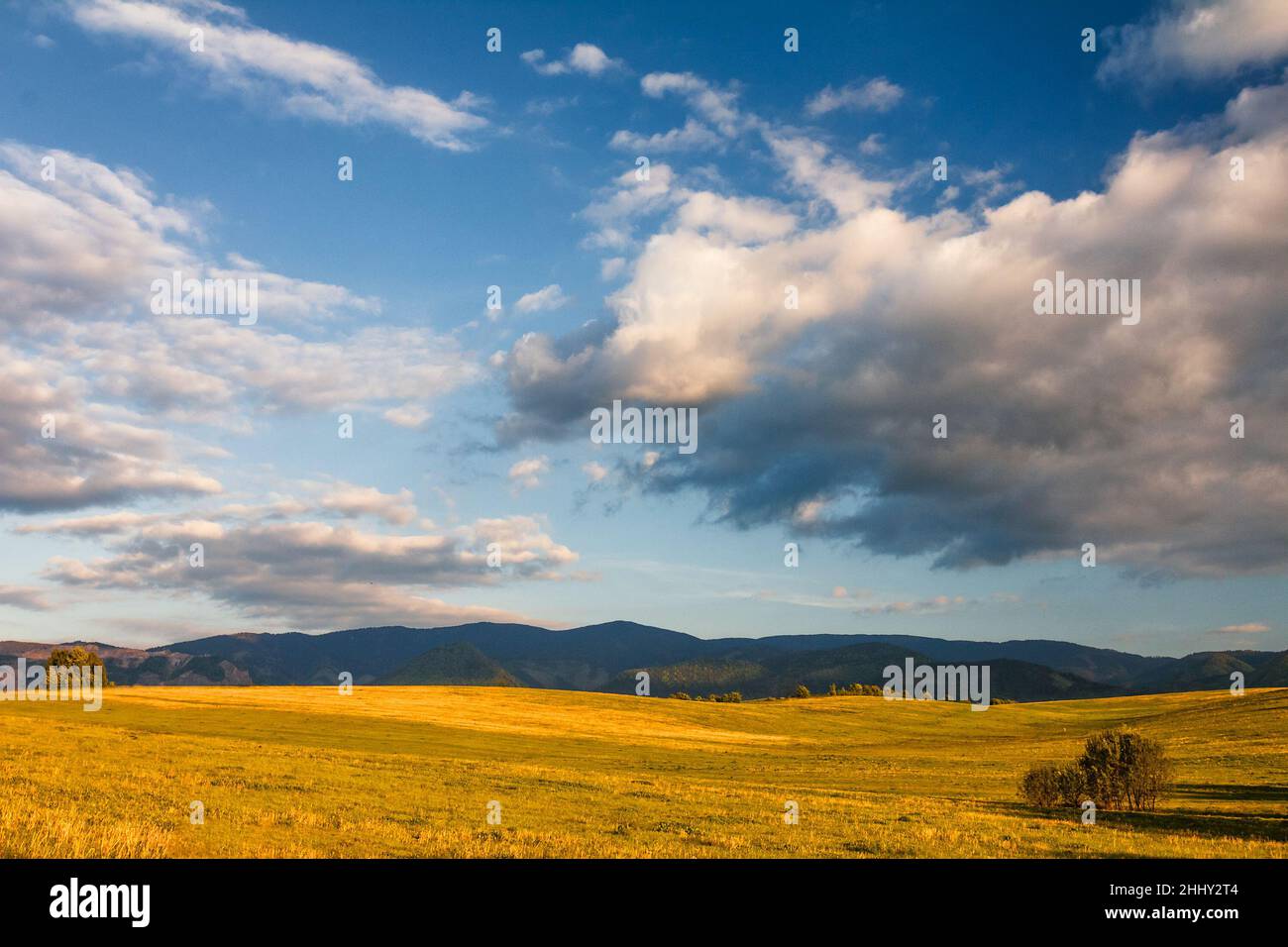 Paesaggio soleggiato con montagne e cielo blu con le nuvole sullo sfondo. Foto Stock