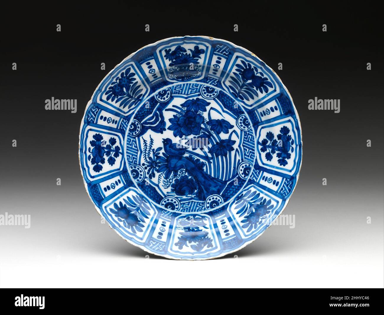 Piatto con fiori e uccelli ca. 1660 olandese, Delft molto probabilmente introdotto dal mondo islamico, dove si era sviluppato nel nono secolo in risposta alle ceramiche cinesi importate, l'uso di uno smalto a base di stagno per coprire un corpo di terracotta scuro ha una lunga storia in Europa. Qui, lo smalto di stagno è verniciato con pigmento blu su una piastra la cui forma e disegno parallelo porcellana kraak ware. Piatto con fiori e uccelli 196577 Foto Stock