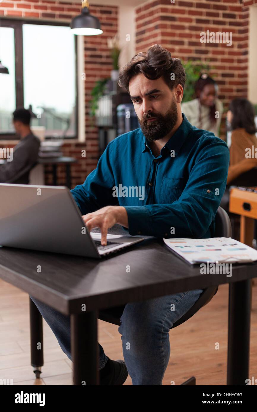 Businessman occupato che analizza le statistiche aziendali digitando strategia di marketing pianificazione collaborazione aziendale. Uomo imprenditore brainstorming idee mentre si lavora a mattone parete startup ufficio Foto Stock