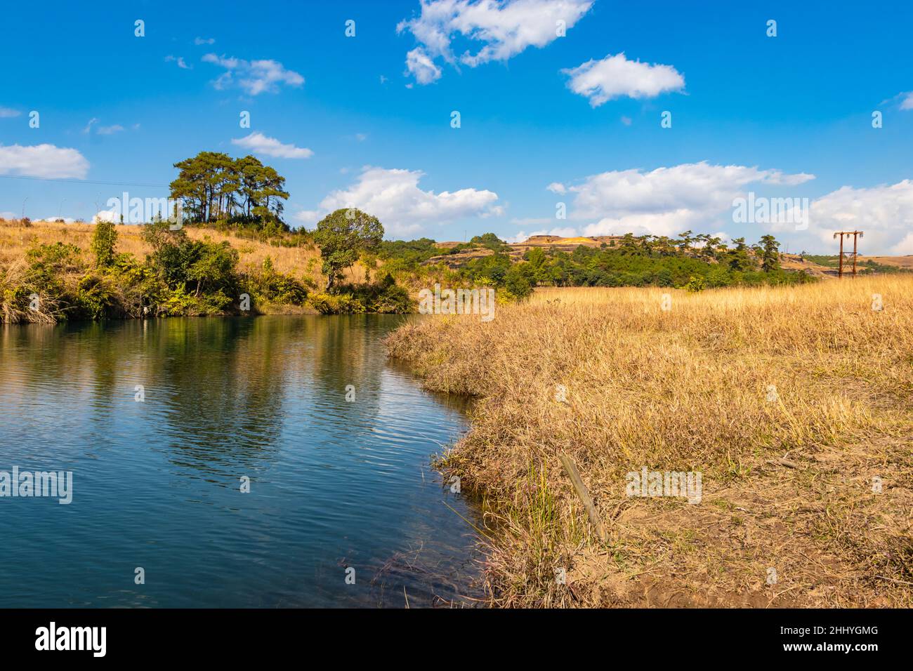 riverside giallo erba campi di campagna con cielo blu luminoso al mattino da angolo piatto immagine presa su sohra caduta meghalaya india. Foto Stock