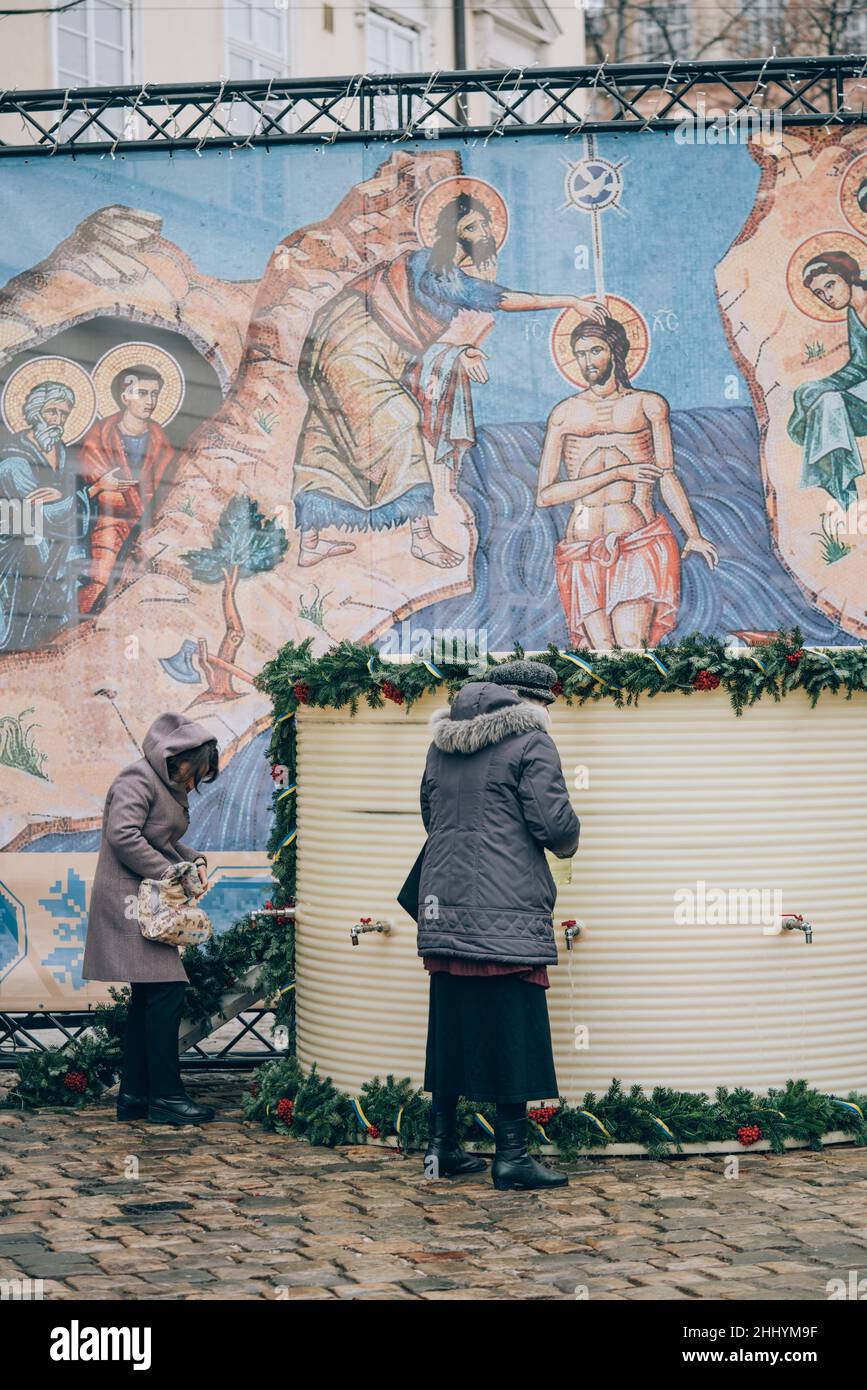 Lviv, Ucraina - 19 gennaio 2022 : Epifania, vacanze ortodosse. Persone che raccolgono acqua Santa consacrata in bottiglie e contenitori per portarla a casa Foto Stock