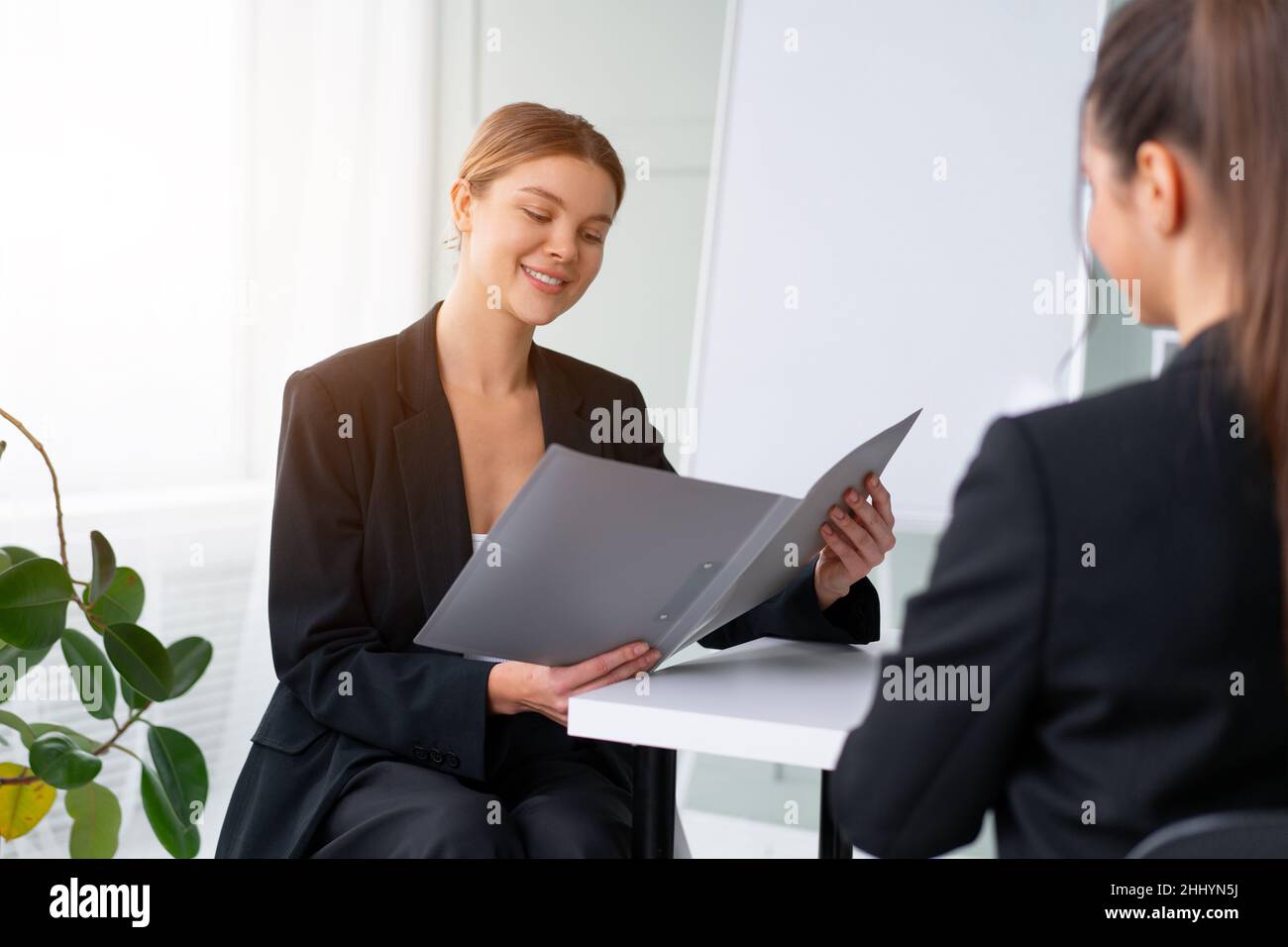 Colloquio di lavoro. Concetto di business, carriera e collocamento. Giovane donna bionda che tiene il resume, mentre seduta davanti al candidato durante la riunione corporativa Foto Stock