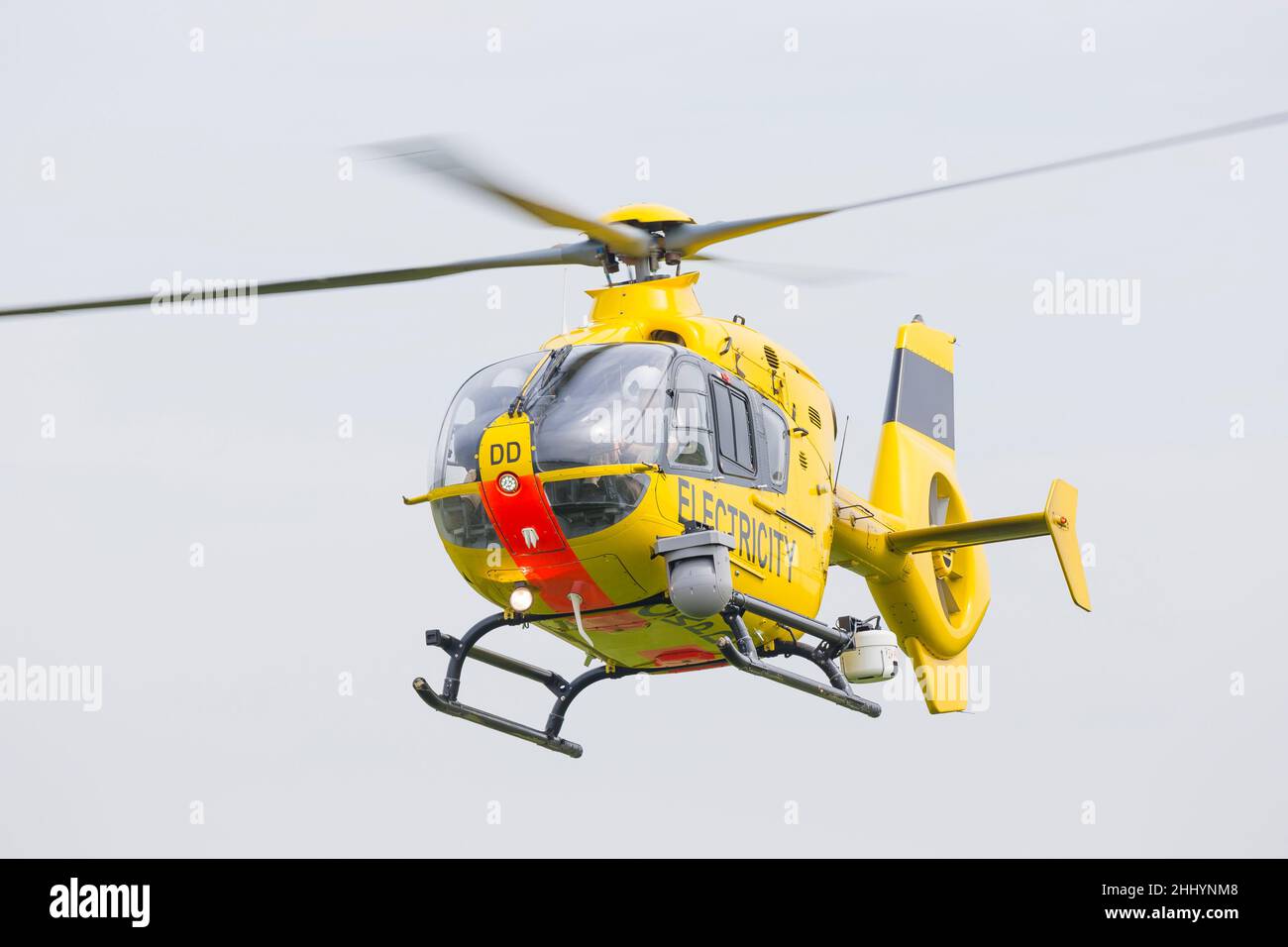 Elicottero giallo WPD (utilizzato nell'industria della distribuzione di energia elettrica per la manutenzione/riparazione della rete e l'ispezione della linea elettrica) che vola isolato in cielo. Foto Stock