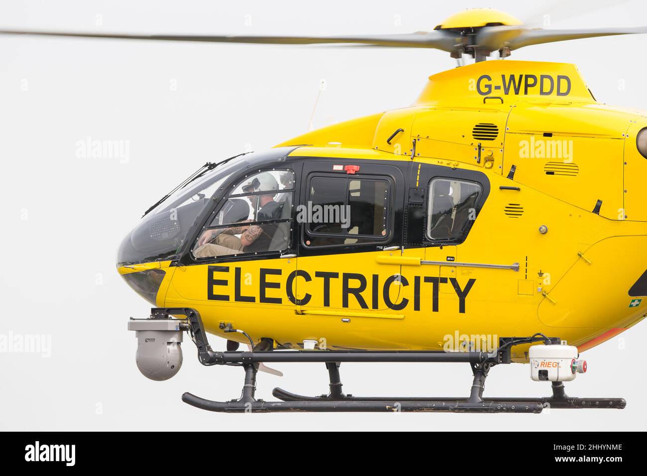 Elicottero giallo WPD (utilizzato nell'industria della distribuzione di energia elettrica per manutenzione/riparazione/ispezione della linea elettrica) che vola isolato in cielo. Foto Stock