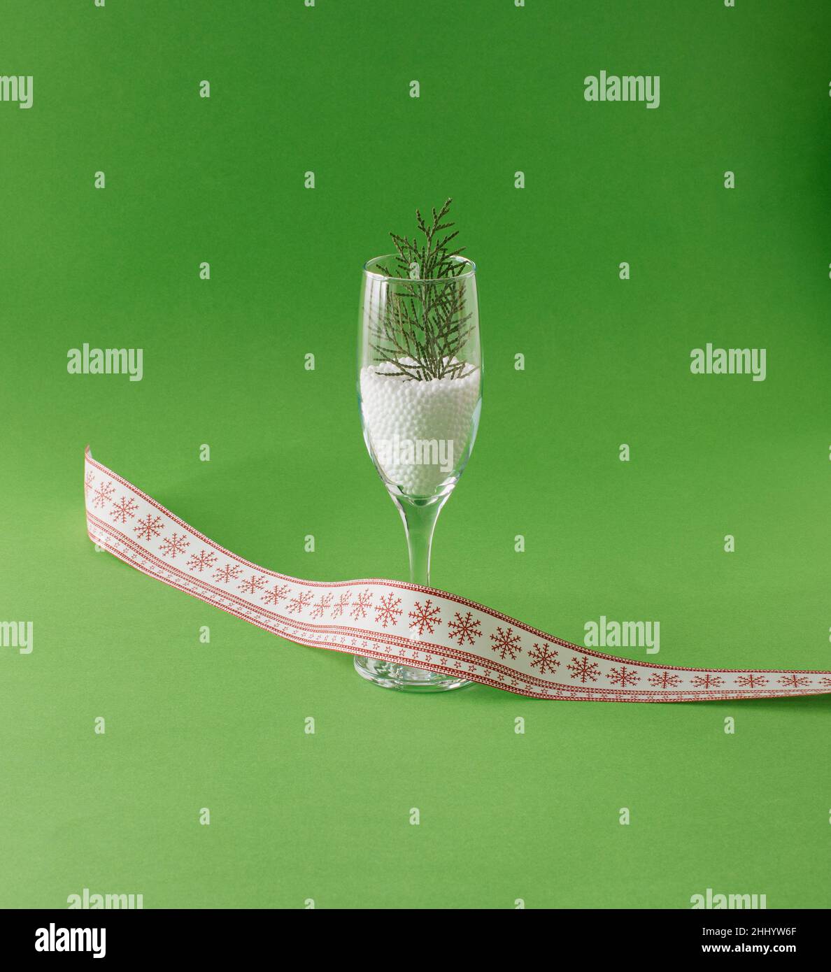 Capodanno composizione di un bicchiere con fiocchi di neve e un albero di Natale. Su sfondo verde. Concetto minimo. Foto Stock