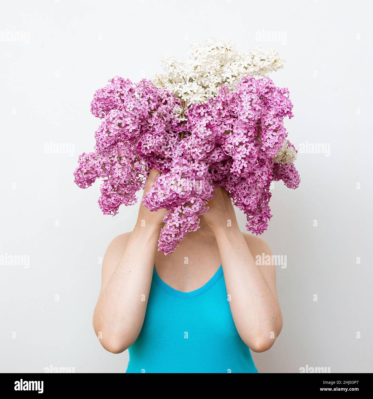 Ragazza timida nel vestito blu nascondendosi dietro fiori lilla. Concetto modesty Foto Stock