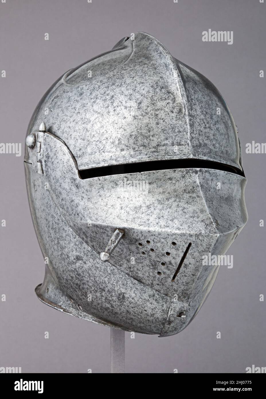 Armet ca. 1490 Italiano il termine armet è generalmente utilizzato per indicare un casco vibrato di particolare costruzione, uno nel quale grandi gancetti sono incernierati alla base della ciotola appena sopra le orecchie e si chiudono davanti al mento. L'apertura della faccia è formata nello spazio tra il bordo della vaschetta ed i bordi degli zigomi, un'area chiusa e protetta da una breve visiera appuntita incernierata a perni su entrambi i lati della vaschetta. Il lato destro della visiera è dotato di una fessura e di fori per la ventilazione e di una spina di sollevamento. Una fronte cuspide rinforzano rivettata sulla parte anteriore della ciotola, e un cerchio Foto Stock