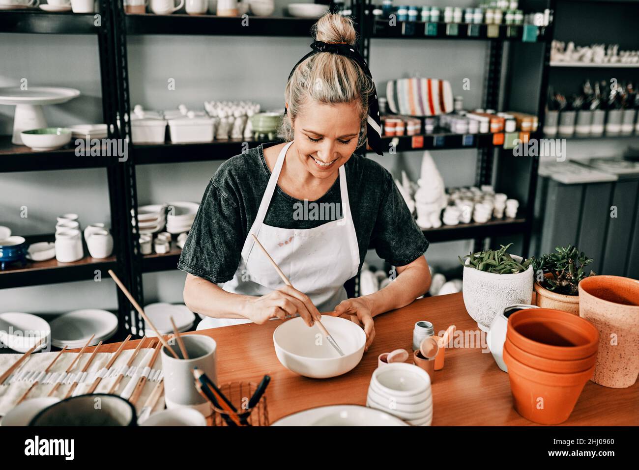 Tempo di dipingere. Scatto corto di una donna matura attraente seduta da sola e dipingere una ciotola di ceramica nel suo studio. Foto Stock