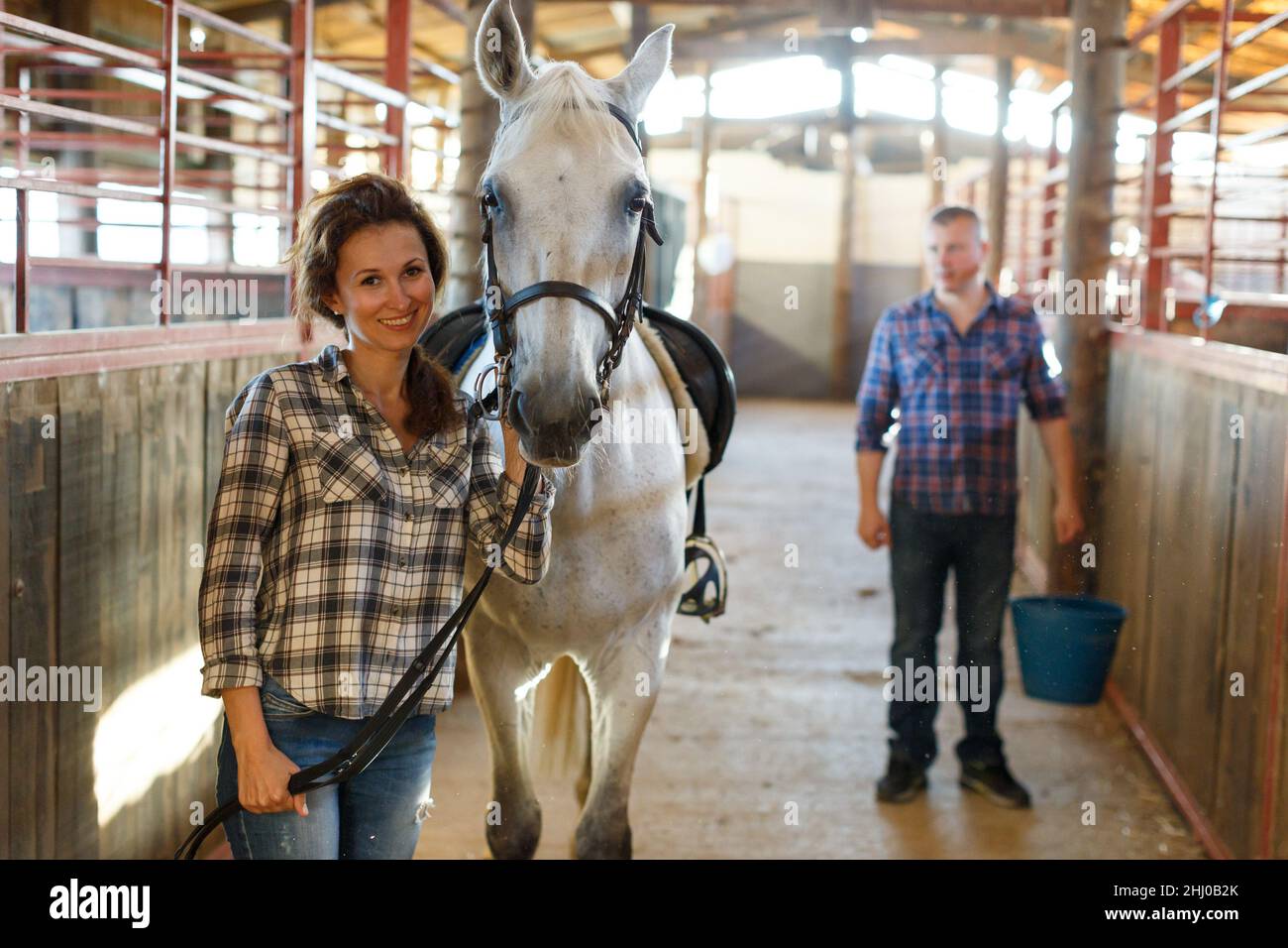 Contadina in piedi con cavallo, il lavoratore di sesso maschile pulizia  pavimento a stalle Foto stock - Alamy