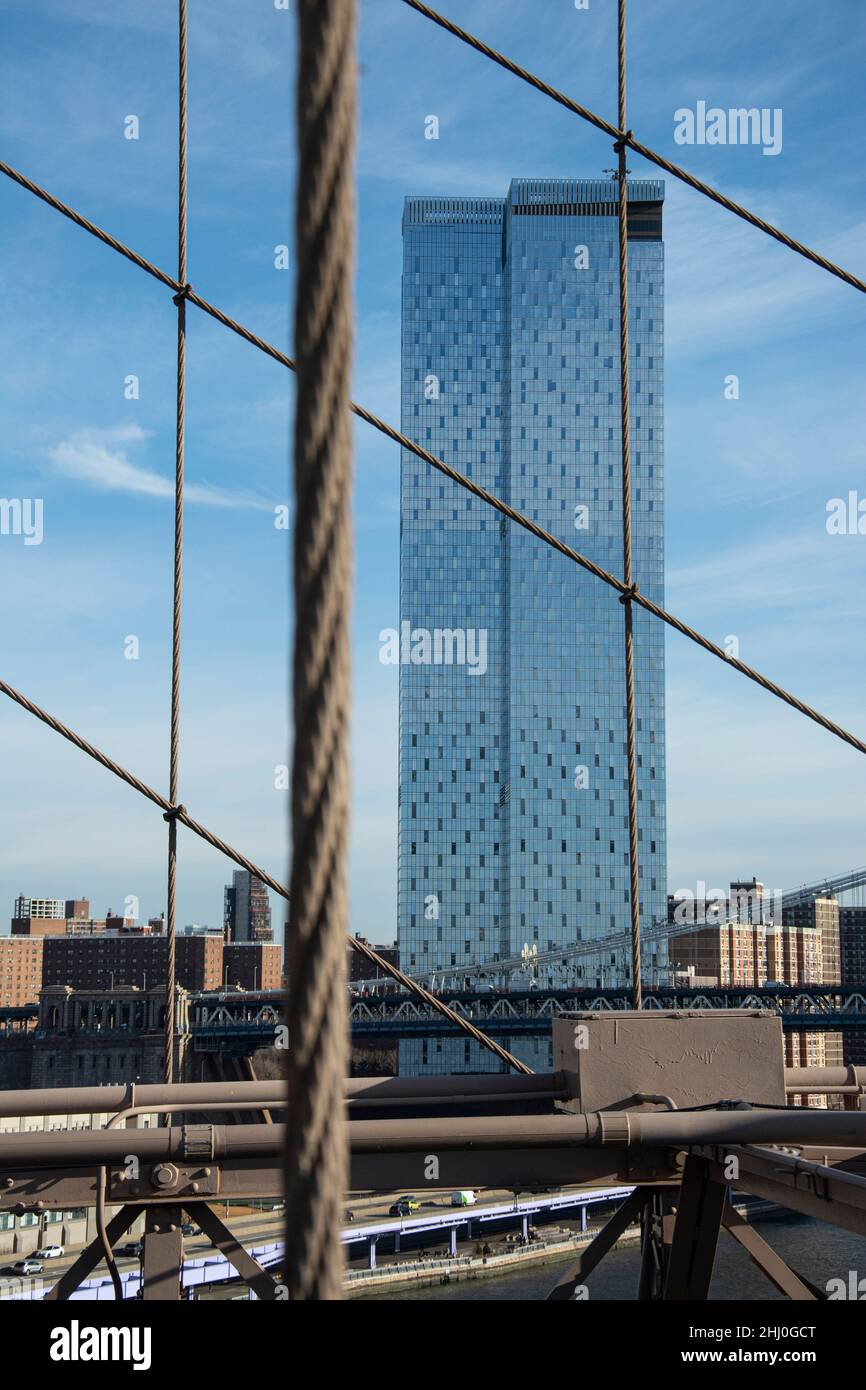 Die Stahlträger der Brooklyn Bridge mit einem Hochhaus im Hintergrund Foto Stock