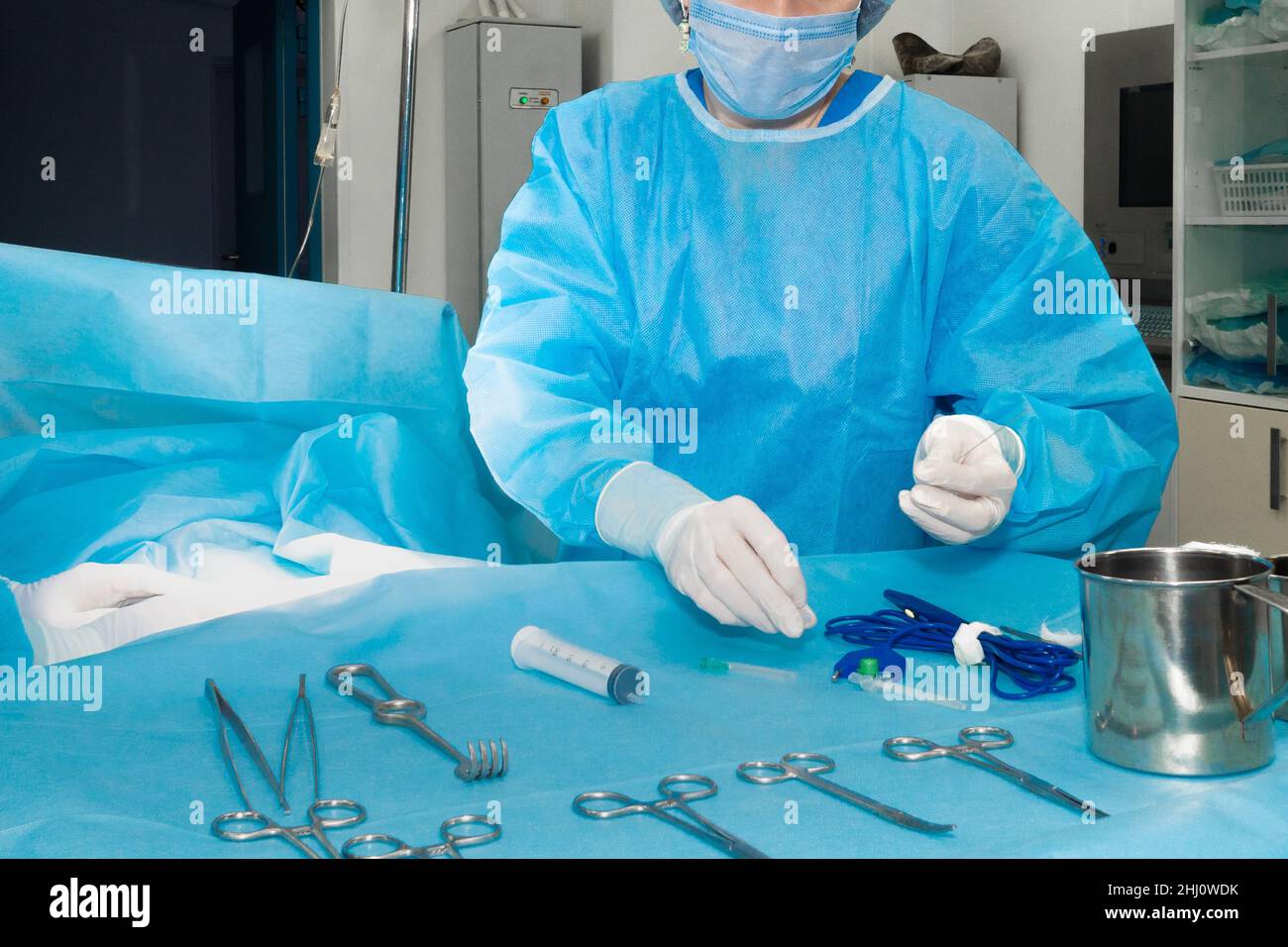 Mani di un chirurgo in guanti bianchi che lavorano con strumenti chirurgici sterili durante l'intervento chirurgico, primo piano. Foto Stock