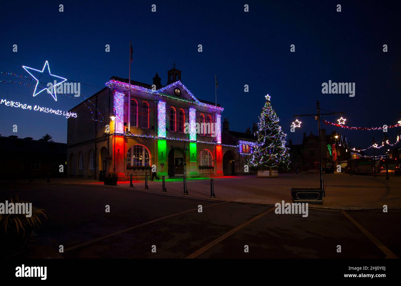 Luci colorate di Natale Melksham Townhall Wiltshire Inghilterra UK albero di Natale centro città copia spazio mercato luogo cielo chiaro notte tempo Foto Stock