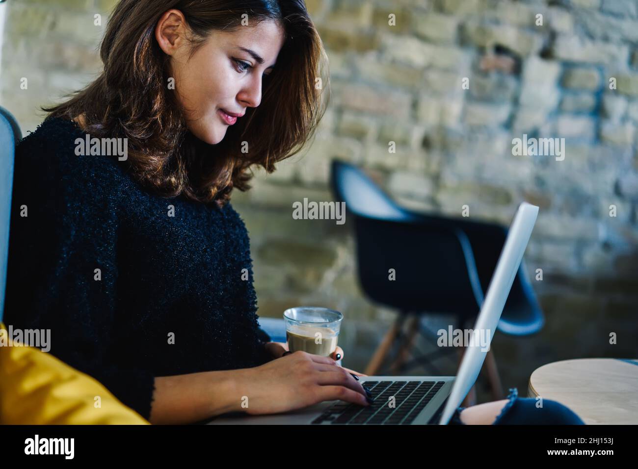 Giovane donna che naviga su un laptop nella moderna caffetteria Foto Stock