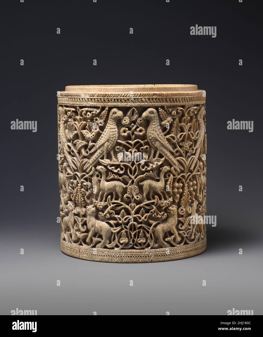 Pyxis ca. 950–75 Spagnolo questa squisitamente scolpita scatola cilindrica si ritiene sia una delle opere più compiute di un maestro del palazzo del califfo Umayyyyad ‘Abd al-Rahman III (r. 912–61), che governava la maggior parte della penisola iberica. A giudicare da altri esempi, il coperchio a cupola mancante di questa scatola probabilmente aveva un’iscrizione che indicava il nome del proprietario e la data. I pixidi islamici, noti come ushnan in arabo, erano esclusivamente secolari e venivano usati per conservare gioielli e cosmetici. L'incorporazione di uccelli, leoni e gazzelle in mezzo riccamente scolpiti rotoli di vite è tipico di densa Isla simmetrica Foto Stock