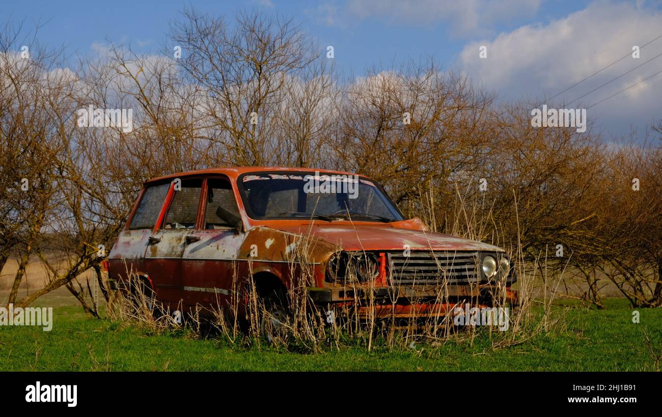 Auto vecchia, arrugginita, rossa, rumena, comunista inghifed dalla natura catturata all'inizio della primavera Foto Stock