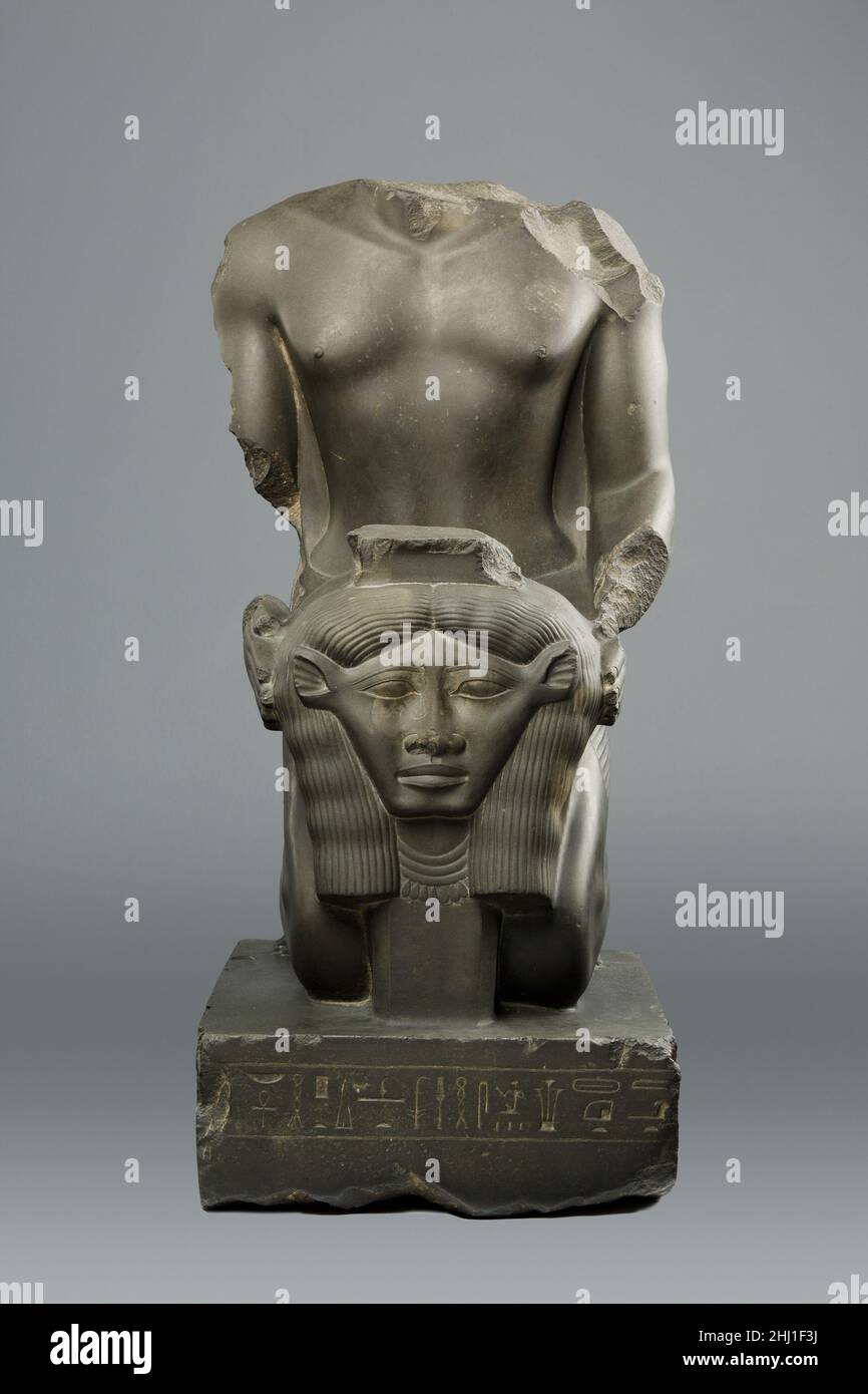 Inginocchiando la statua di Amenemopetemhat 664–610 a.C. nel tardo periodo, Saite Amenemope-em-hat fu direttore dei cantanti del Nord e Overseer dei cantanti di Amenemope. Il secondo titolo fu ereditato dal padre, la cui statua altrettanto bella è stata scoperta recentemente a Tanis, dove c'era un culto di Amenemope, una forma del dio Amun. Il primo titolo implica più ampio authority.Amenemope-em-Hat tiene davanti a lui l'oggetto di culto della dea mucca-eata Hathor. Le proporzioni di questa figura, la sua muscolarità, e dettagli come le creste inclinate del collarbone e la depressione poco profonda dow Foto Stock