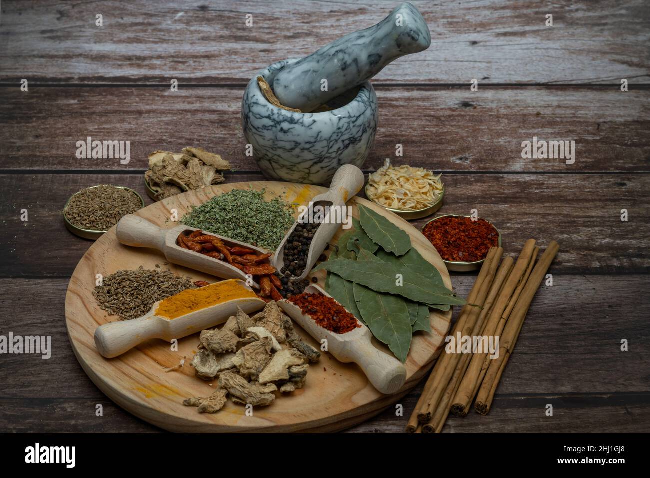 diversi tipi di spezie in cucchiaio di legno e malta per la loro preparazione fuori fuoco Foto Stock