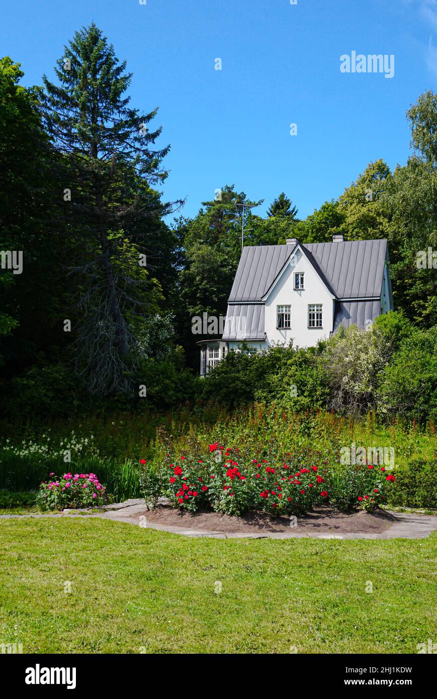 La casa di campagna perfetta circondata da alberi densi e cespugli di fiori Foto Stock