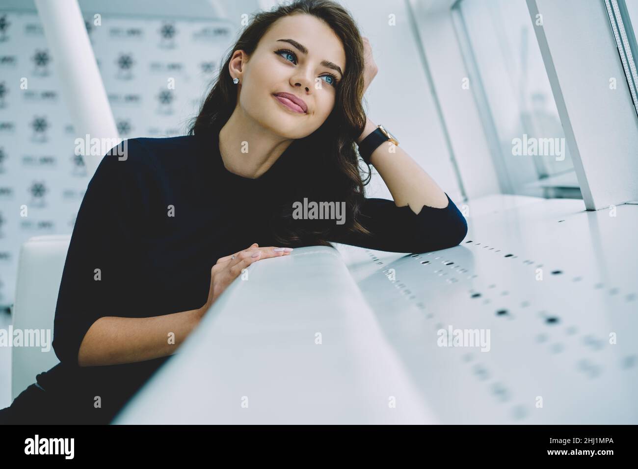 Giovane donna seduta sul divano bianco e guardando verso l'alto Foto Stock