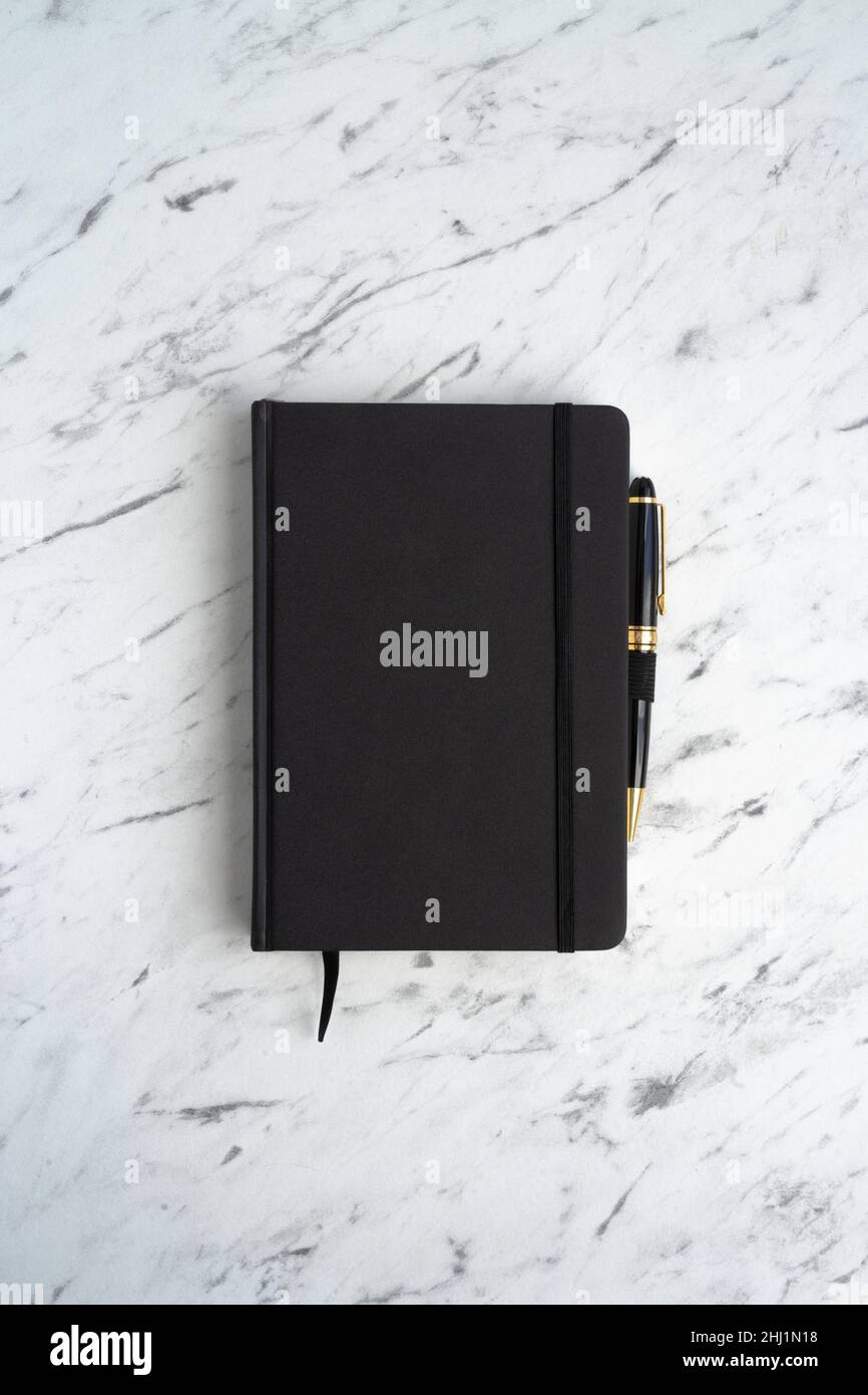 Notebook nero con penna su un tavolo in marmo, vista dall'alto Foto Stock