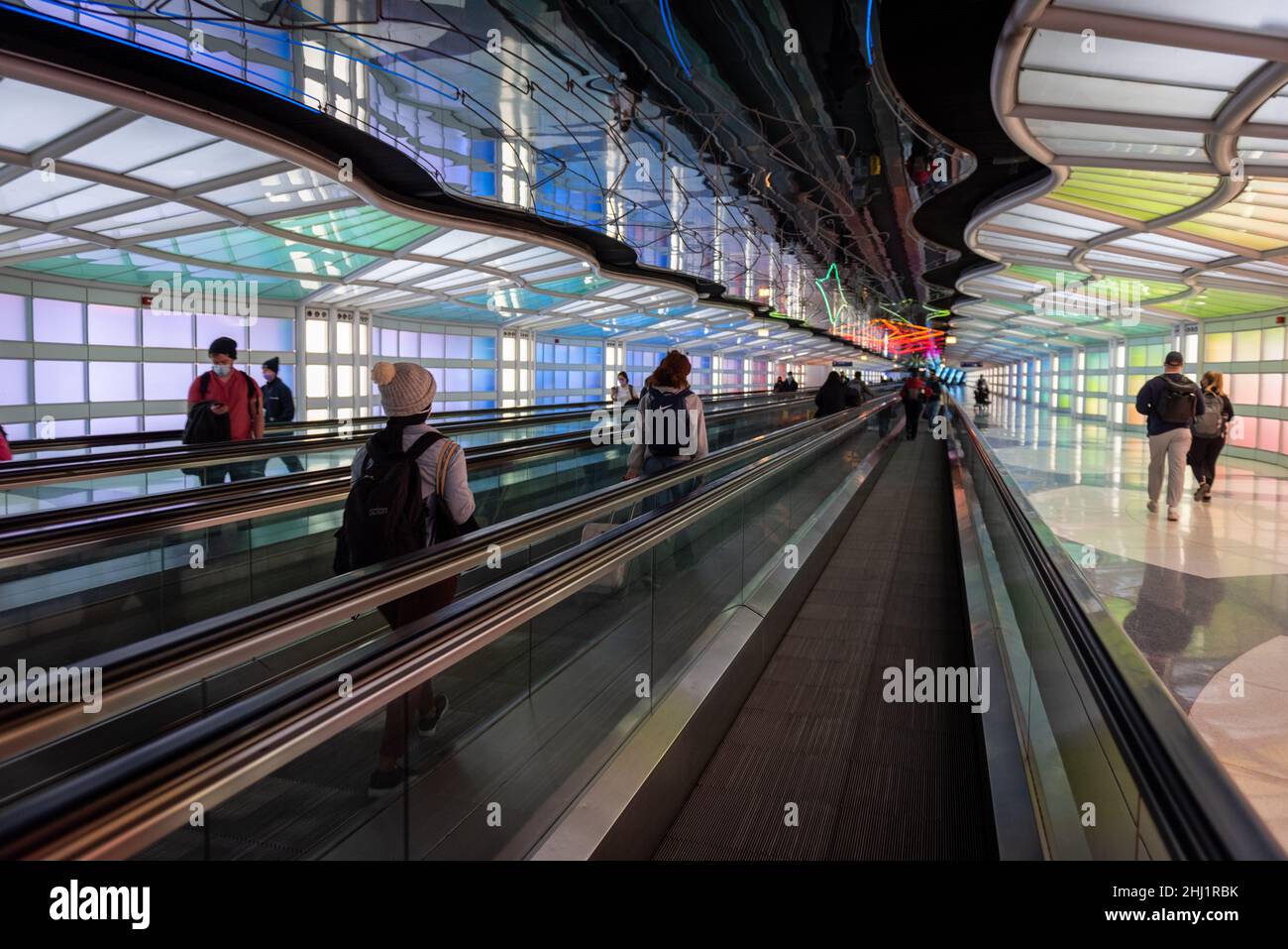 I passeggeri del trasporto aereo, business la gente camminare e colorati di luci al neon installazione d arte da Michael Hayden, tunnel pedonale, Chicago O'Hare Airport Terminal. Foto Stock