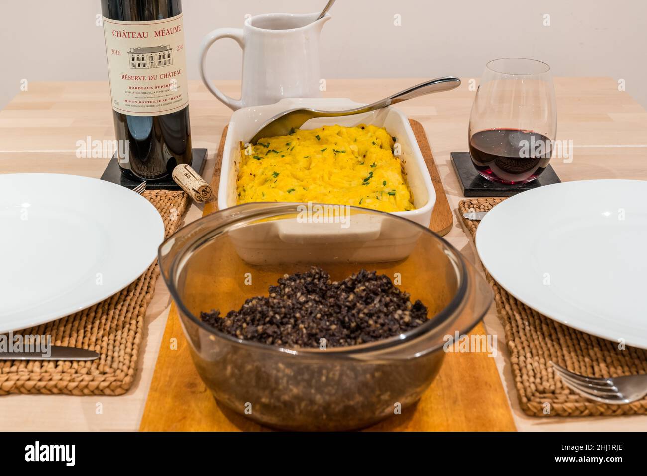 Cena tradizionale scozzese a base di Burns Night: haggis & Clsnapshot (purè di patate e rapa o sudore) e bottiglia di vino rosso Chateau Meaume di Bordeaux Foto Stock