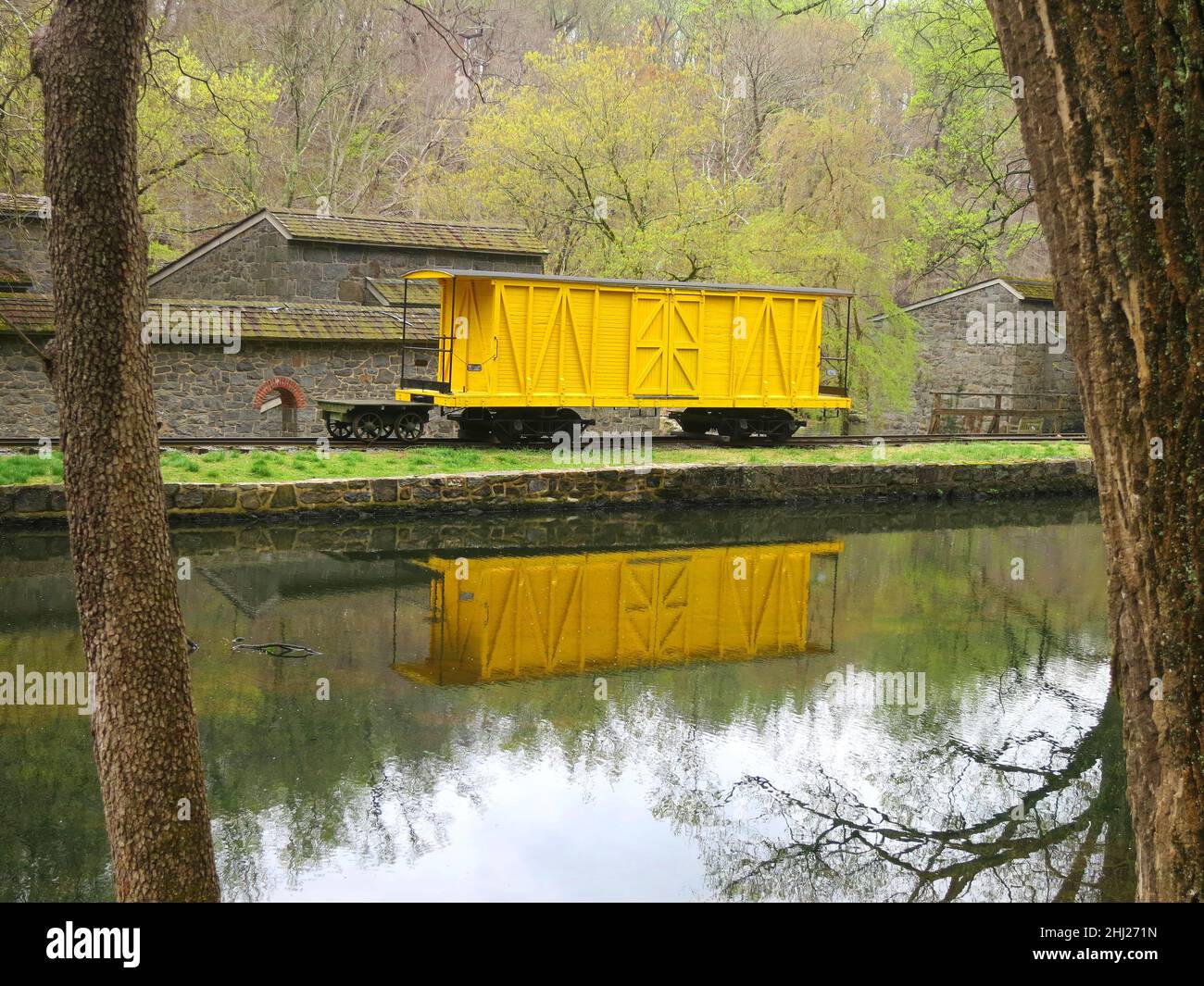 Vintage Train box auto giallo su binario laterale con riflessi in un canale. Foto Stock