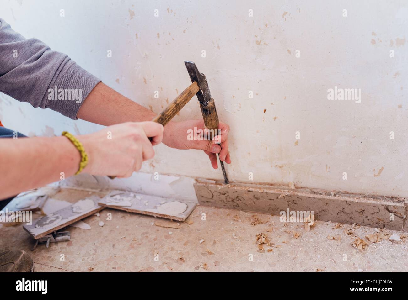 Rimuovere il battiscopa con un martello e uno scalpello. Foto Stock