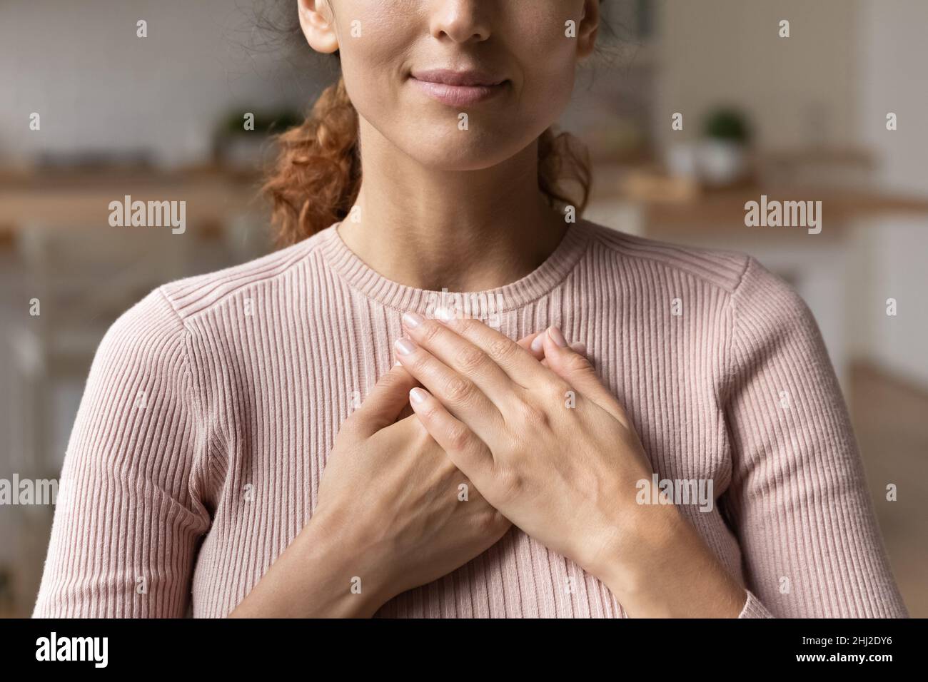 Donna sincera ha messo le palme piegate sul petto sensazione di gratitudine primo piano Foto Stock