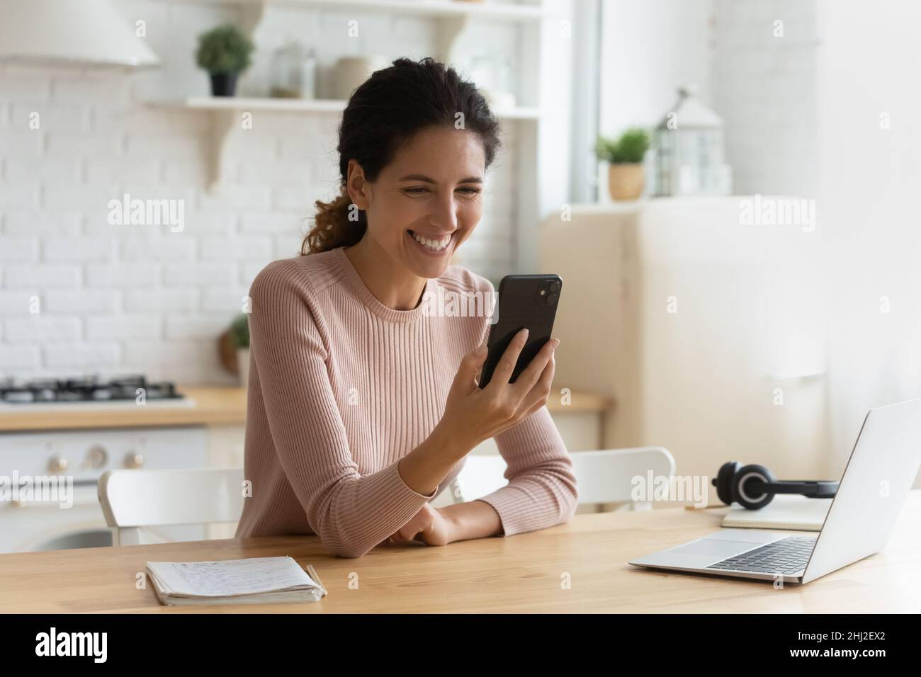 Femmina sit indoor con smartphone moderno che ride al video online Foto Stock