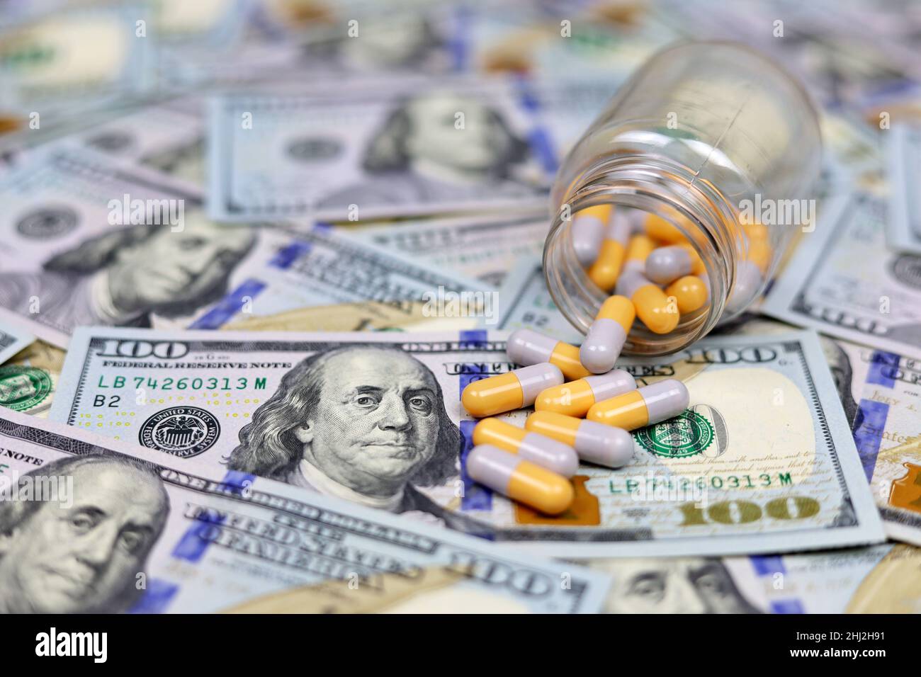 Pillole in capsule sparse da una bottiglia su dollari US valuta. Concetto di assistenza sanitaria negli Stati Uniti, commercio farmaceutico, prezzi della droga, farmacia Foto Stock