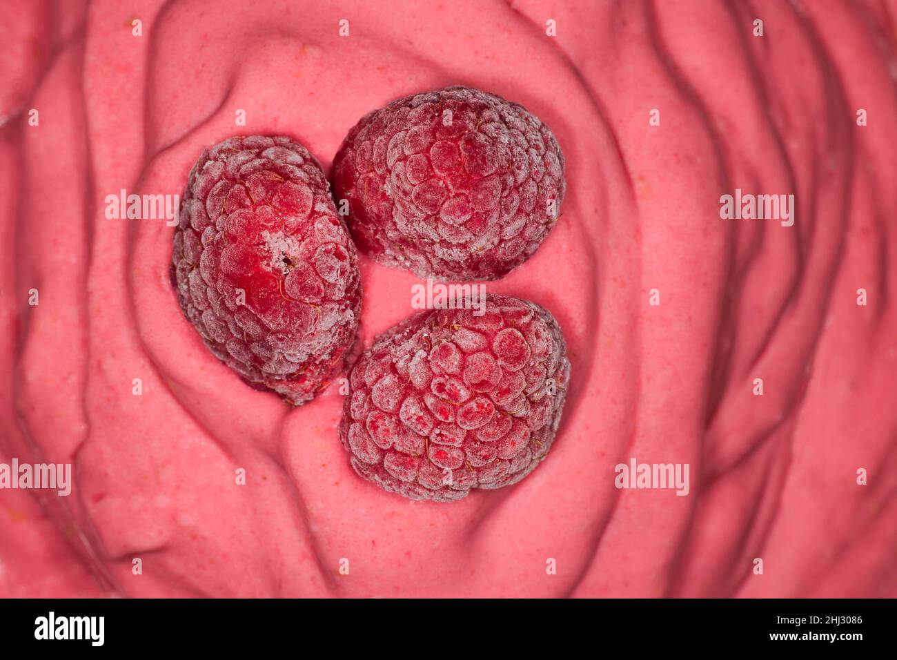 Tre lamponi congelati su un gelato al lampone Foto Stock