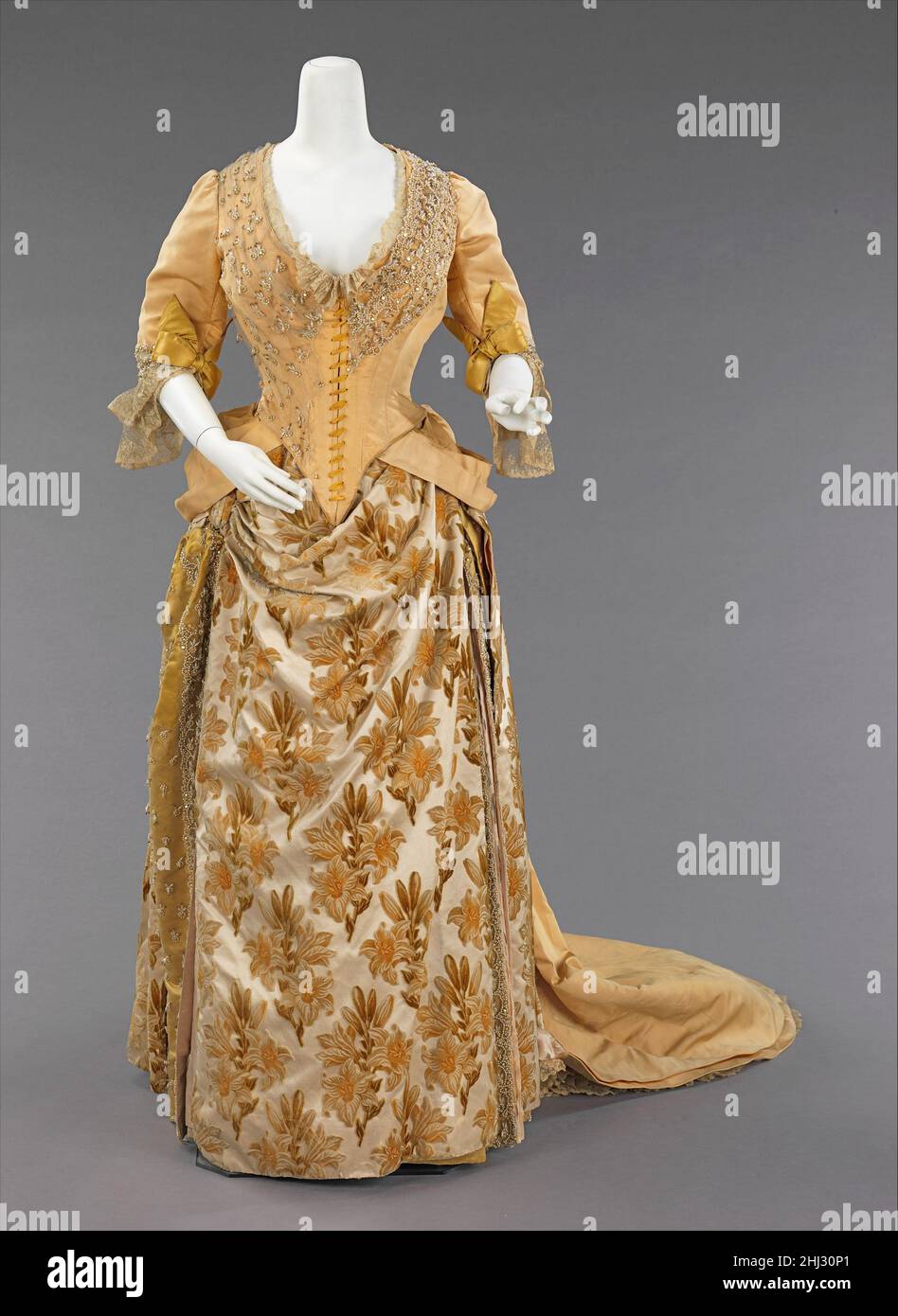 Ensemble serale ca. 1888 Casa del valore francese la silhouette trambusto, anche se associata principalmente alla seconda metà del 19th secolo, ha avuto origine in prima moda come un semplice urto sul retro del vestito, come con fine 17th-inizio 18th secolo mantuas e fine 18th-inizio 19th secolo abiti Impero. La silhouette piena di trambusto ebbe il suo primo aspetto vittoriano alla fine del 1860s, che iniziò come pienezza nelle gonne che si spostavano verso la parte posteriore del vestito. Questa pienezza è stata elaborata in legami per camminare che ha creato un puff alla moda. Questo puff trendsetting si espanse ed è stato poi bu Foto Stock