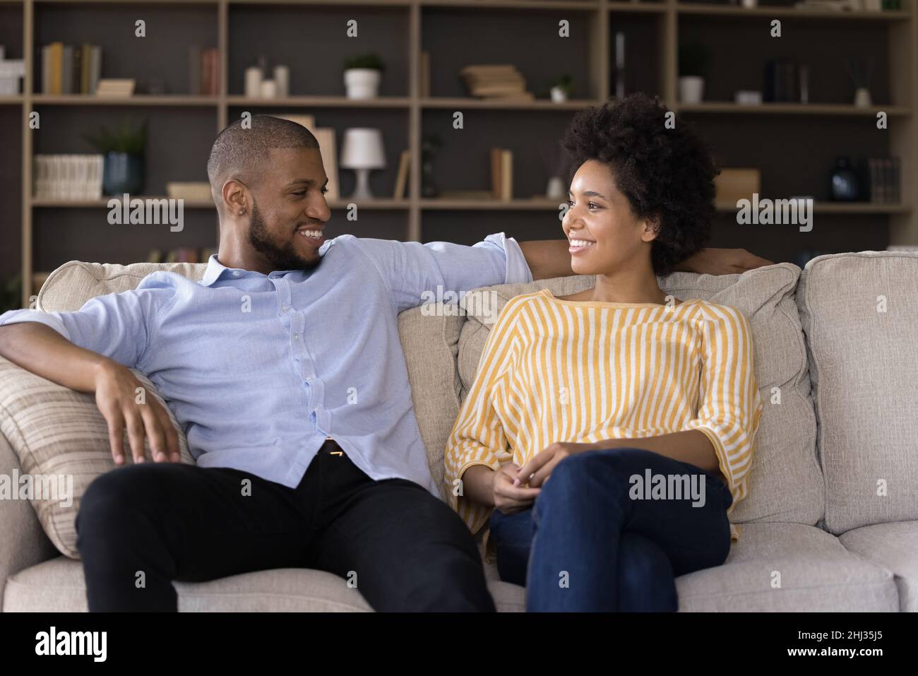 Coppia africana che ha conversazione seduto sul divano a casa Foto Stock